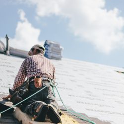 Roofer adding shingles to the roof of a house